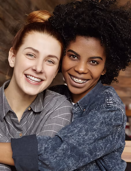 A smiling woman with her arm around her same-sex partner.