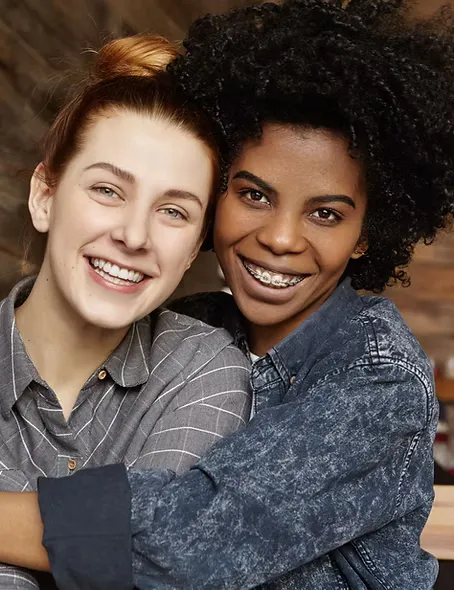 A smiling woman with her arm around her same-sex partner.